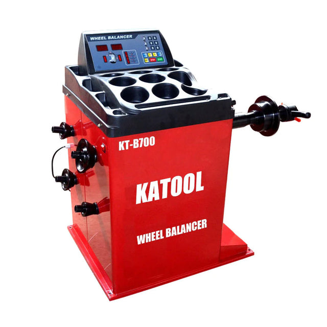 Red KATOOL KT-B700 wheel balancer with digital display, control buttons, and wheel mounting spindle for tire balancing.